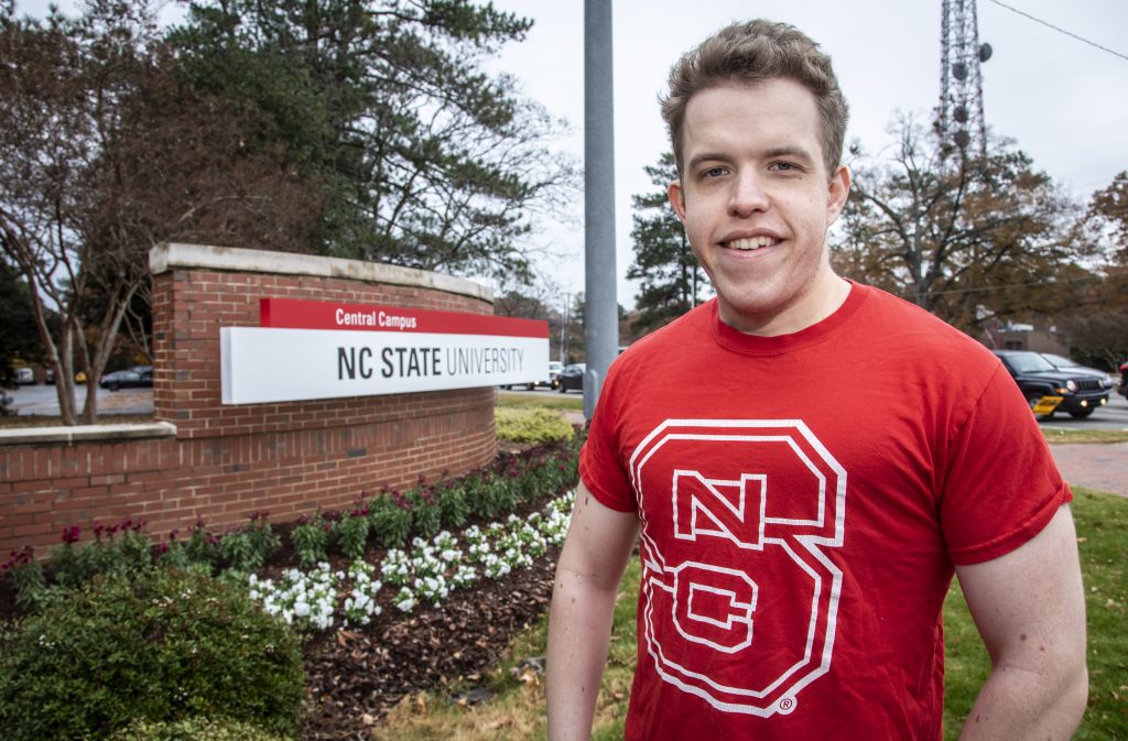 Male student in front of NC State sign