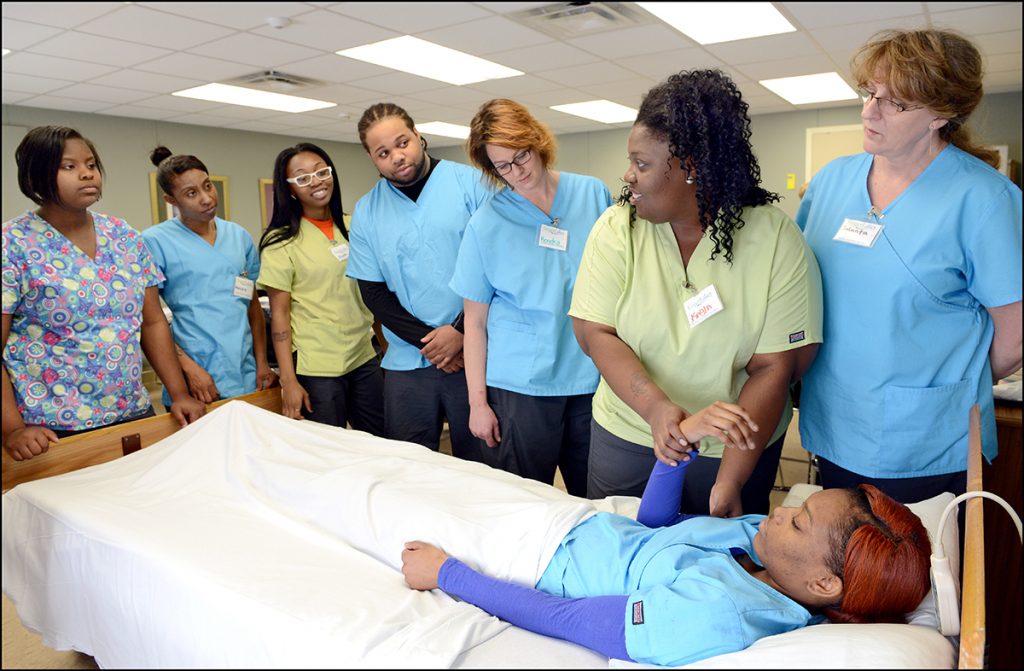 Nurse assistant students watching demonstration at patient bed