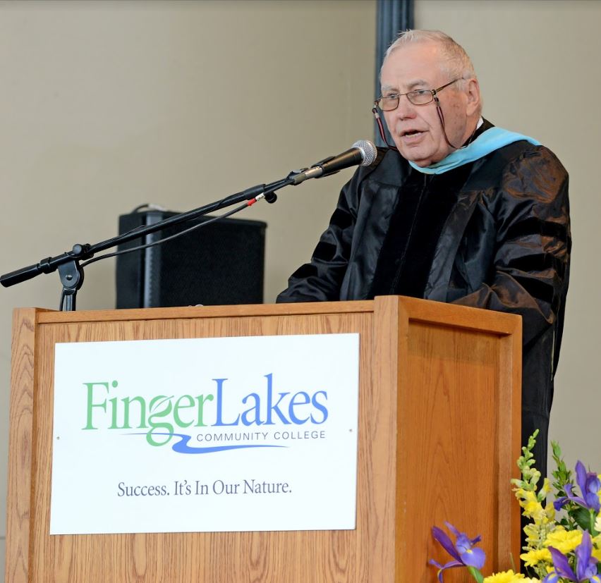 Dr. Kennedy in academic regalia at a podium