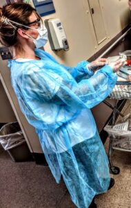 Nurse in blue gown puts on PPE in a hospital