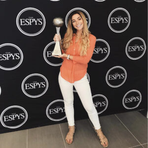 Woman holding a trophy in front of an ESPN banner