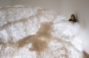Photo of woman behind a large cloudlike art installation