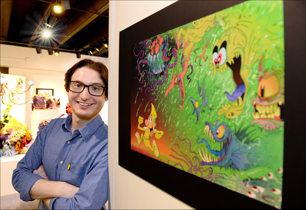  Ryan Kovar '12, poses with one of his illustrations. Photo by Rikki Van Camp