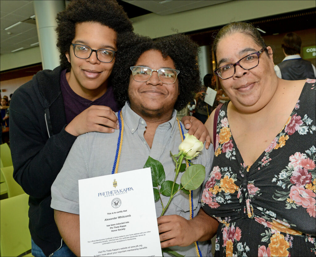 Student posing with PTK certificate and two family members